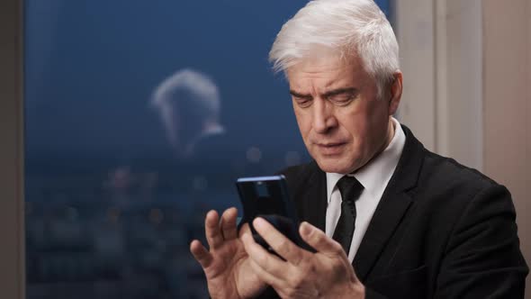 Focused White Businessman in Blazer Scrolling Phone