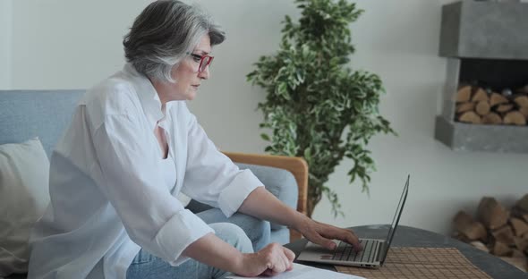 A Thoughtful Senior Serious Businesswoman Analyzes a Company's Financial Report alt