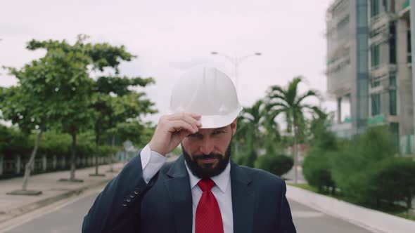 Portrait Senior Industrial Engineer in Business Suit Adjusting His White Safety Helmet Looking alt