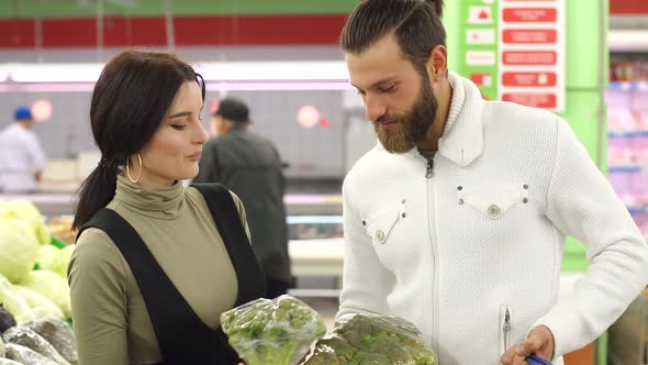 Beautiful Young Smiling Couple Choosing Cauliflower in Supermarket Together alt