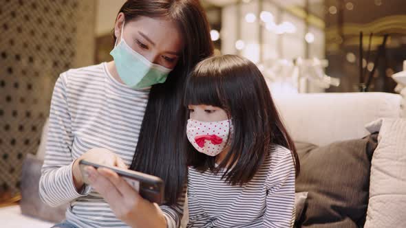 Asian young mother wearing face mask for  kid at home  prevent Covid 19 infection alt