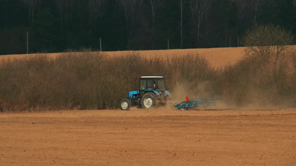 Tractor with a Cultivator Working in an Agricultural Field alt