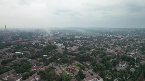 Aerial View of the City Near a Large Industrial Plant with Pipes and Smoke alt