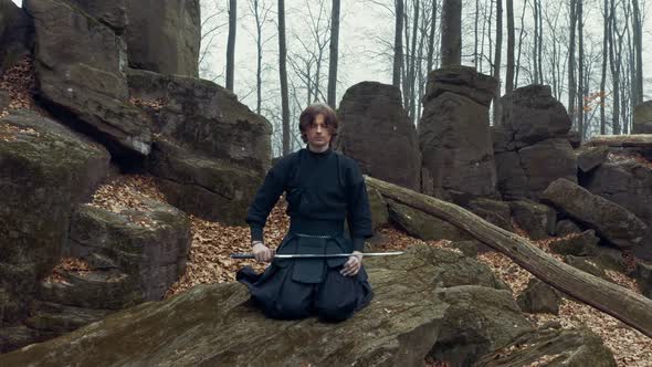 Concentrated Man with a Japanese Sword, a Katana Practicing Iaido in a Pine Forest alt