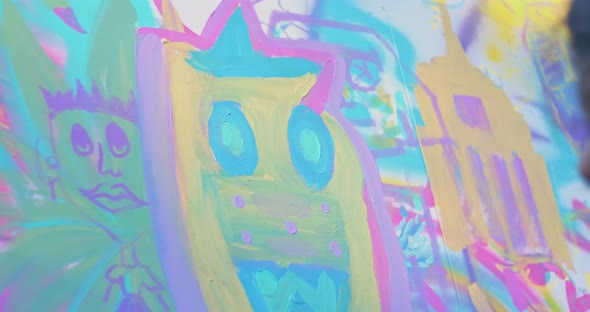 Tight shot of a woman painting a big cloth canvas while holding a paint tray in a public park alt