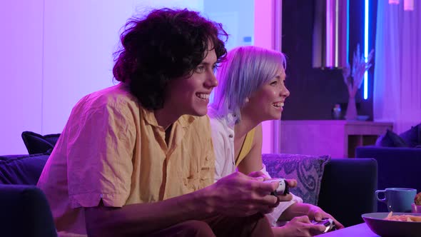 Young Adult Brother Sister Playing Video Games Sitting Room Lit Neon Color Home alt