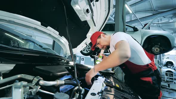 Car Mechanic Uses Flashlight to Inspect Under the Hood of a Vehicle alt