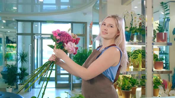 Young Lady in Apron Enjoys Bouquet and Poses for Camera alt