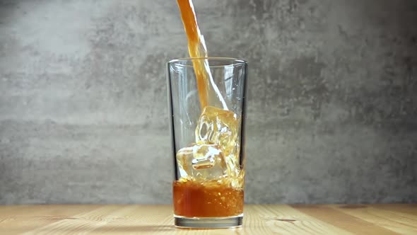 Soft Drink is Poured Into a Glass With Ice Cubes