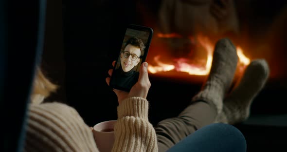 Woman Makes Online Video Call By Smartphone in Cozy Home with Fireplace