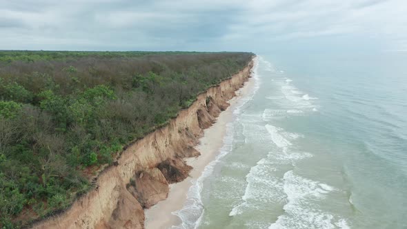 Aerial View of Ocean Waves Beating Against a Rocky Shore on a Wooded Tropical Seaboard alt