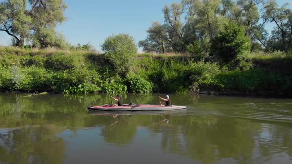 An Aerial View. A Man and a Woman Swim on a Kayak on a River. alt