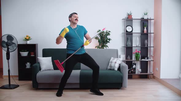 Funny cleaner man with a mustache dances like a rock star and dances to the music.