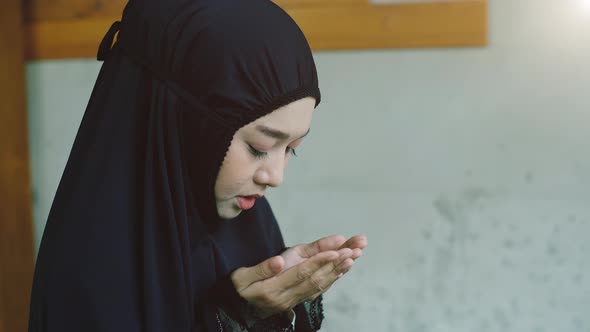 Portrait of an Asian Muslim women in a daily prayer at home reciting Surah al-Fatiha passage of the alt