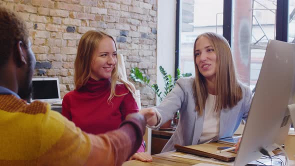 Young Female Designers Shaking Hands with African Client in Office