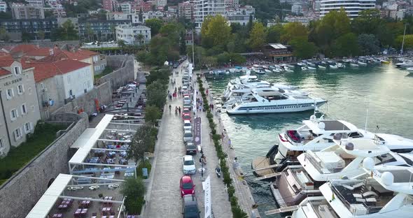 Drone Flies Above Walking Street with Yachts on the Left Side and Old Town on the Right Side