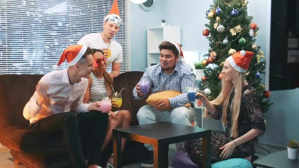 Happy New Year's Celebration in Cheerful Company in Santa Hats and Party Masks alt