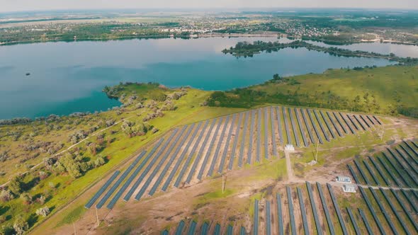 Aerial View on Solar Power Station in Green Field Near River at Sunny Day alt