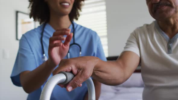 Close up of senior mixed race man with female doctor home visiting holding hands alt