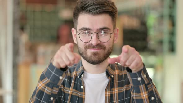 Portrait of Young Man Pointing Finger and Inviting  alt
