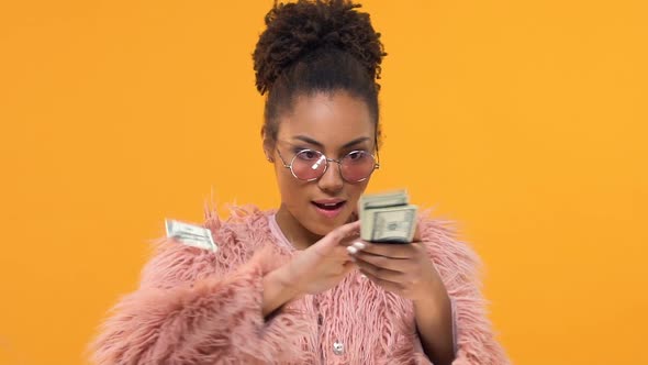 Young Black Female Throwing Around Dollar Bills and Smiling Into Camera, Success alt