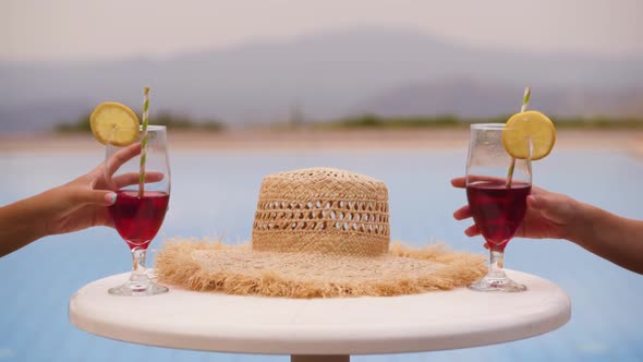 Closeup of Women Lifting Summer Cocktails From Pool Bar Table alt