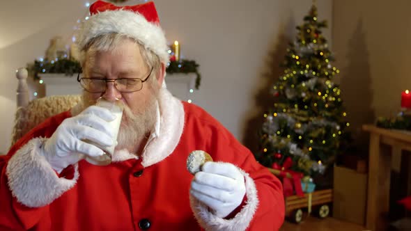 Santa claus relaxing on chair and having sweet food alt