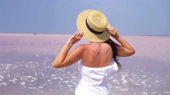 Woman in Hat Walk on a Pink Salt Lake on a Sunny Summer Day