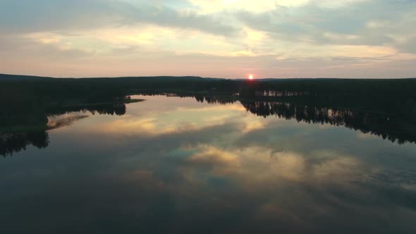 Drone shot of forest and calm lake at dusk