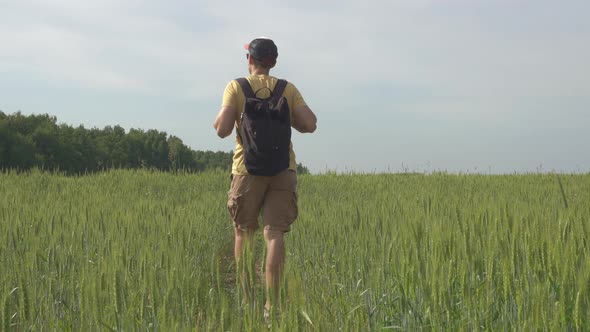 Traveler with a Phone in Nature in the Field Goes on Trekking in the Summer
