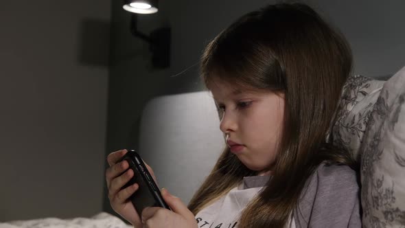 Little Girl Sitting with a Smartphone at Night Games Online Learning
