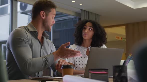 Young office executives discussing over laptop in a modern office alt