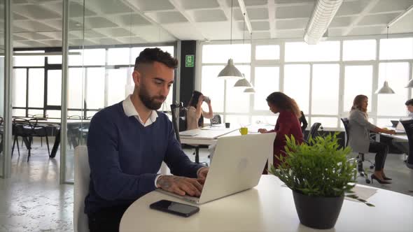 Young man working in coworking space with other people