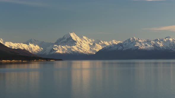 zoom in shot of a calm lake pukaki with a snowy mt cook in the background alt