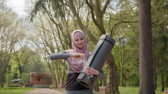 Side View of Pretty Young Woman in Hijab and Activewear Drinking Water From alt