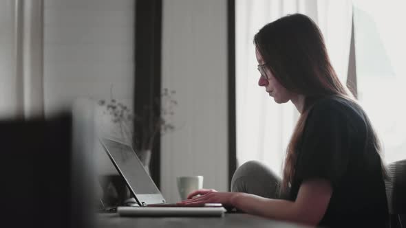 A young man and a young girl are working in front of laptops in their bright apartment. alt