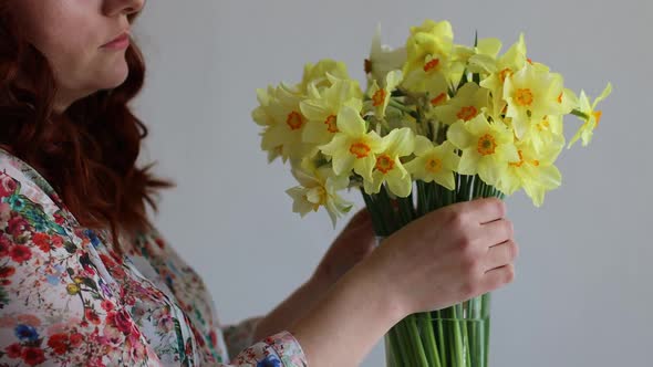 Beautiful Caucasian Girl Puts Flowers in a Glass Transparent Vase with Water