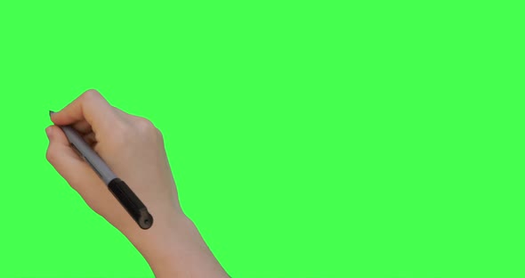 Female hand holding pen and nullifies or crosses out something. Green screen background.  alt