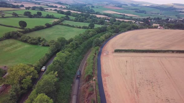 Panning and tracking aerial of a steam training through a busy countryside landscape surrounded by t alt
