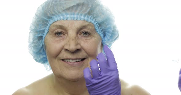 Elderly Female in Protective Hat. Doctor Making Facial Injections for Patient alt