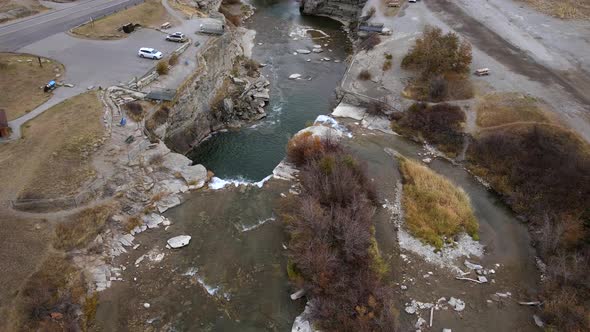 Top down view fly over a waterfall in the Canadian Rocky mountains. Slow motion aerial revealing cam alt