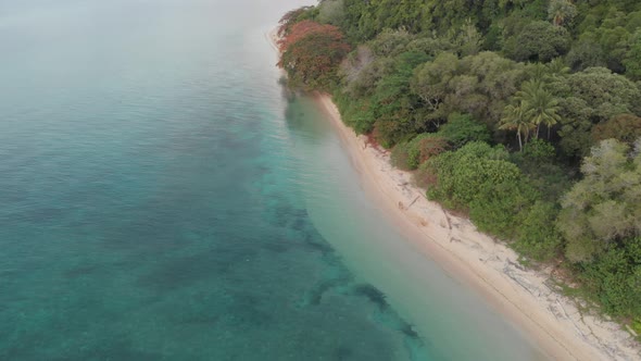 Aerial: flying over tropical island white sand beach Banda Islands Indonesia alt