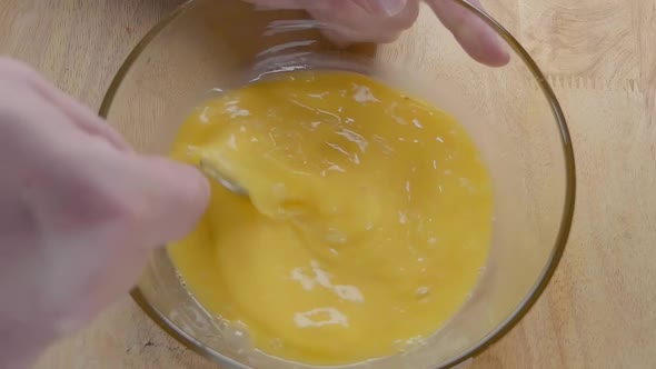 Slow Motion Shot of Whisking Eggs With a Fork in the Kitchen alt