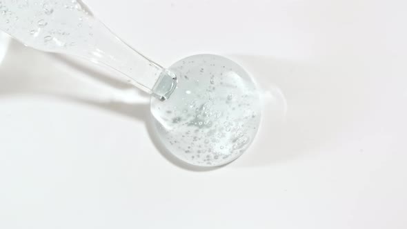 Macro Shot of Transparent Blue Cosmetic Fluid Gel Cream With Bubbles in Pipette Drips on a White alt