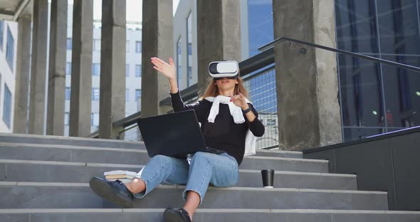 Woman in Casual Clothes Sitting on Steps Outdoors with Laptop on Knees and working alt