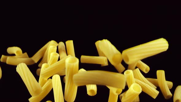 Pasta Rigatoni Flies Up on a Black Background alt
