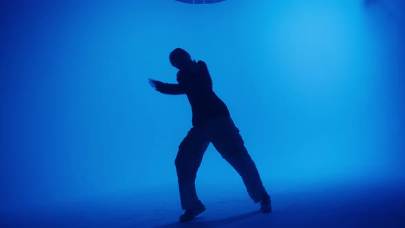Attractive Talented Woman Dancing Hip Hop on Blue Neon Background in Studio alt