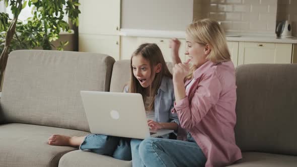Mother and Little Daughter Rejoice at What They See in the Laptop alt