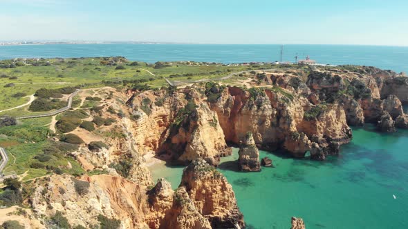 Sea cliffs along Algarve coast towards Ponta Da Piedade lighthouse. Orbiting shot alt