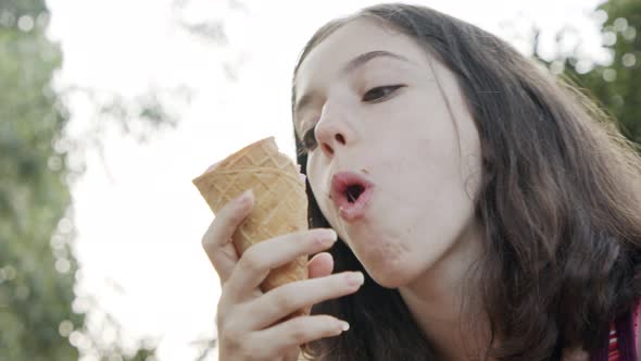 Young girl eating Ice Cream from a cone, enjoying and laughing alt